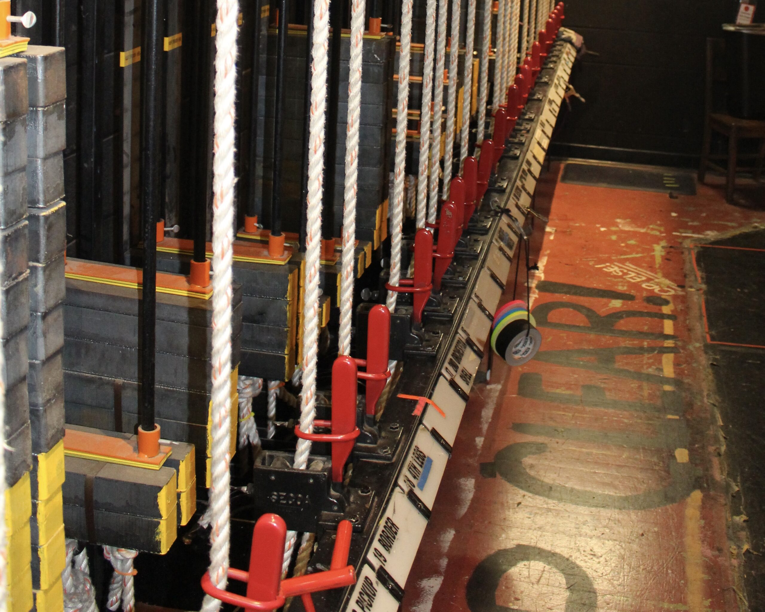 the fly rail of a theaterical stage counterweight rigging system with gaff tape and safety signage - Theater Rigging Inspection